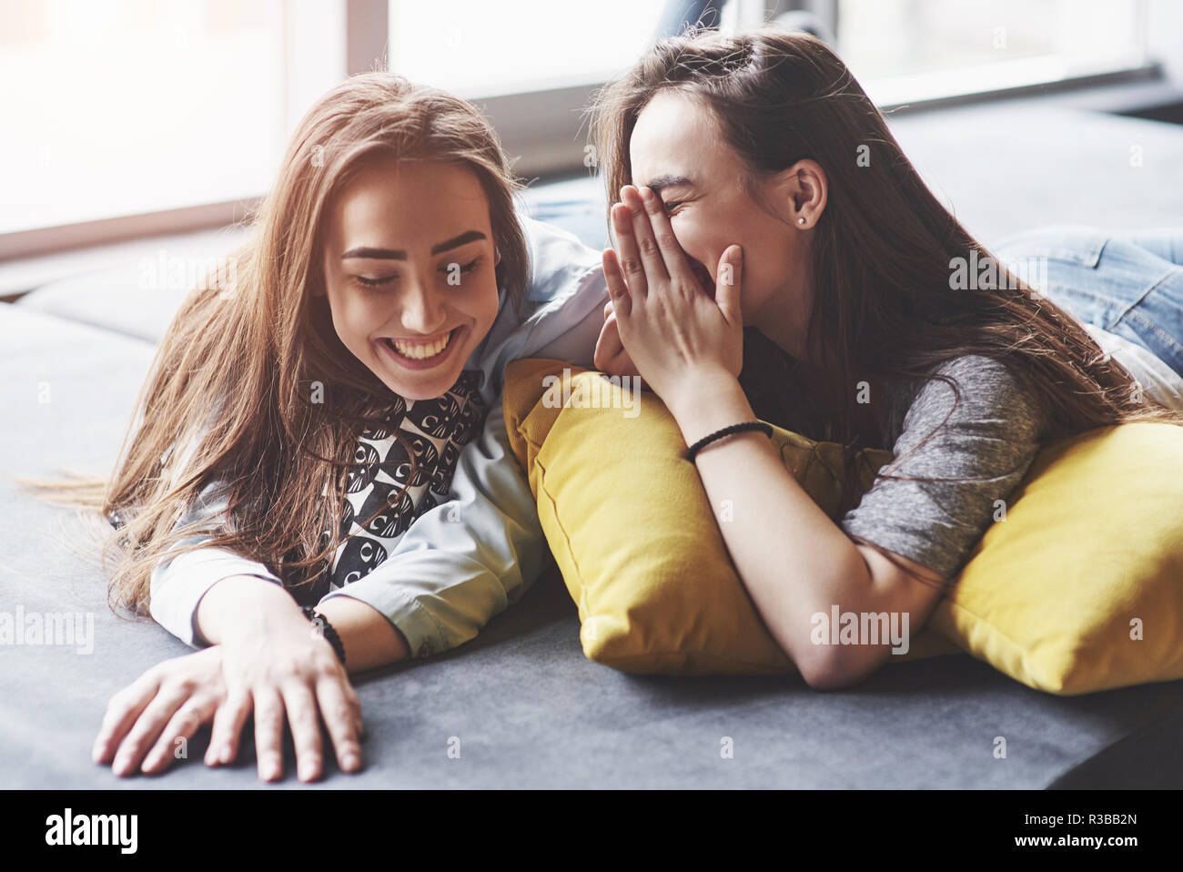 Two beautiful young twins sisters spending time together with pillows. Siblings having fun at home concept Stock Photo