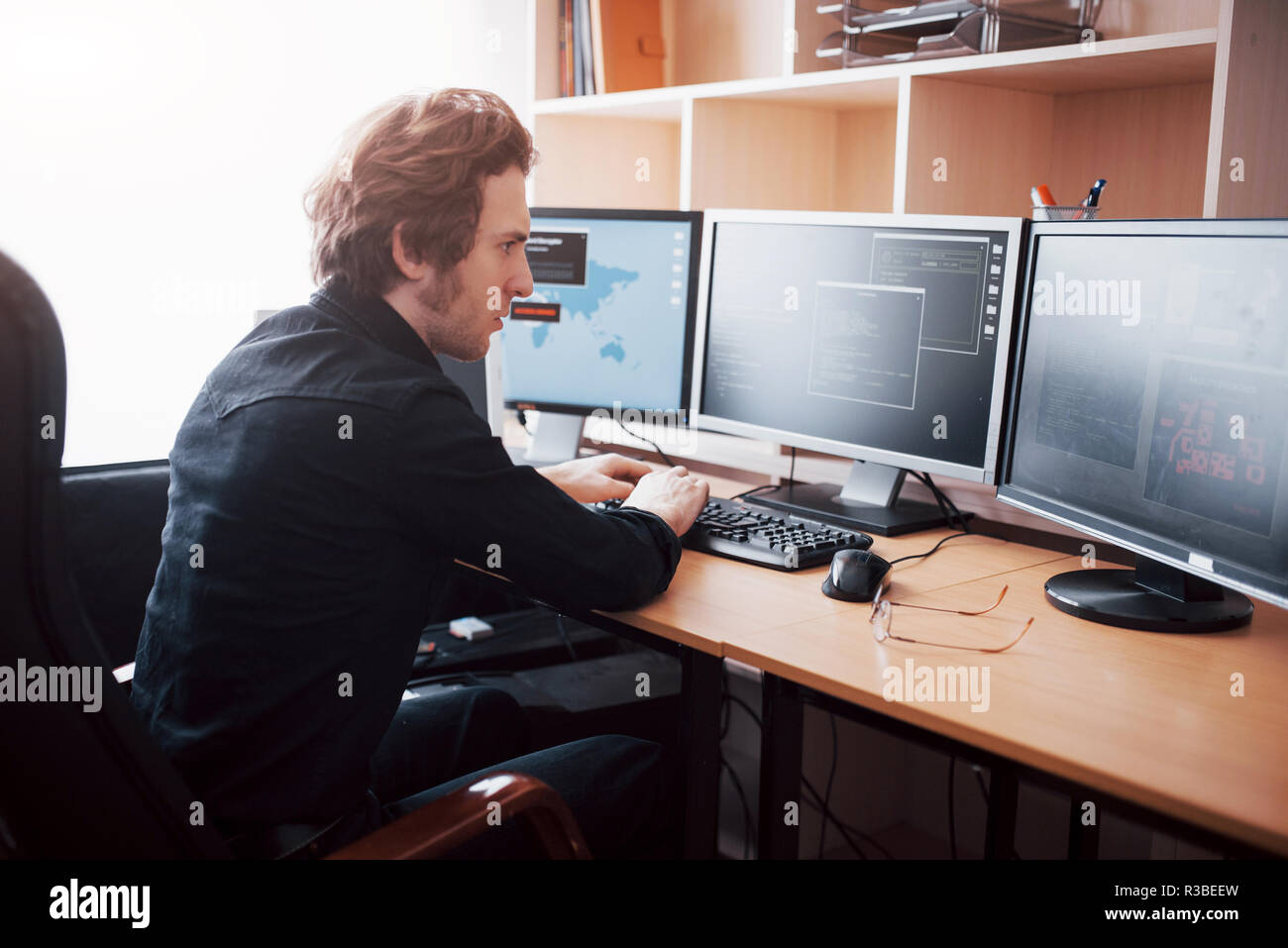 Male programmer working on desktop computer with many monitors at office in software develop company. Website design programming and coding technologies Stock Photo