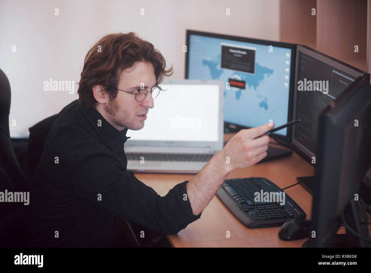 Male programmer working on desktop computer with many monitors at office in software develop company. Website design programming and coding technologies Stock Photo