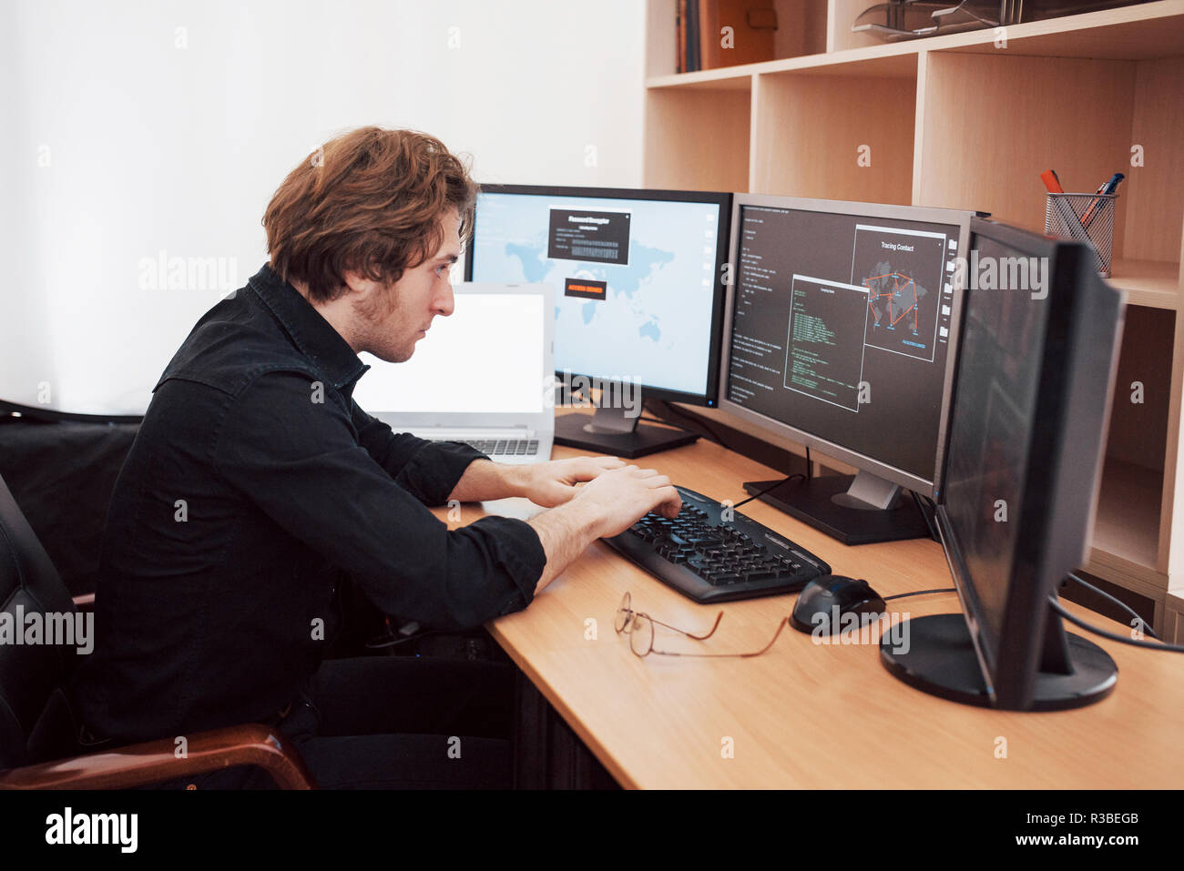 Male programmer working on desktop computer with many monitors at office in software develop company. Website design programming and coding technologies Stock Photo