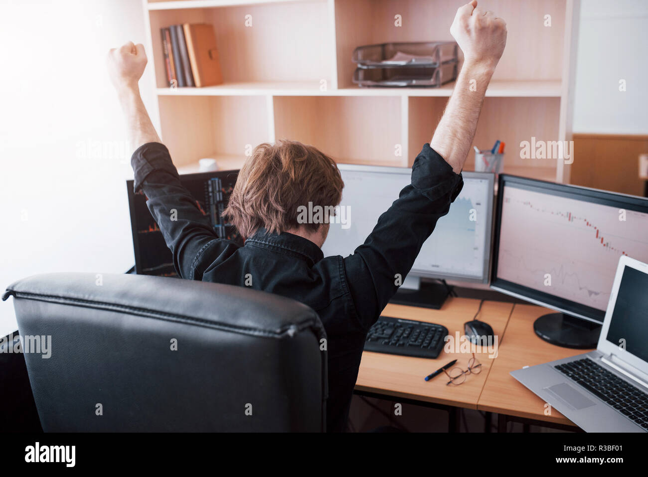 Young stock trader broker stretching hands at workplace, he first achieved great success on the stock market Stock Photo
