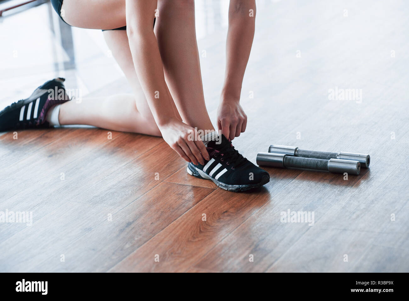 Young girl runner tying her shoelaces. Shot on floor background in
