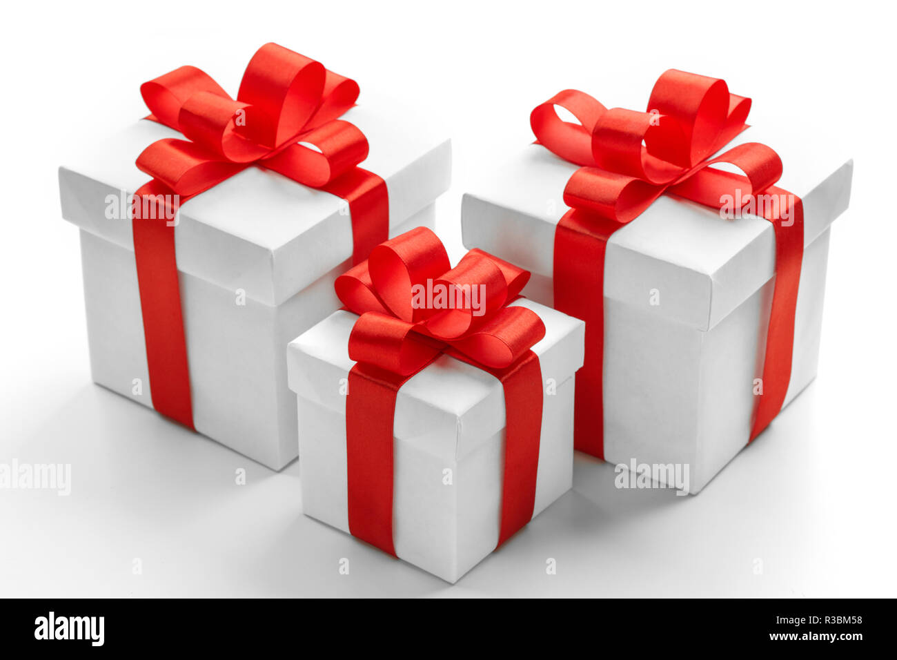 Three gift boxes with red ribbons on white background Stock Photo - Alamy