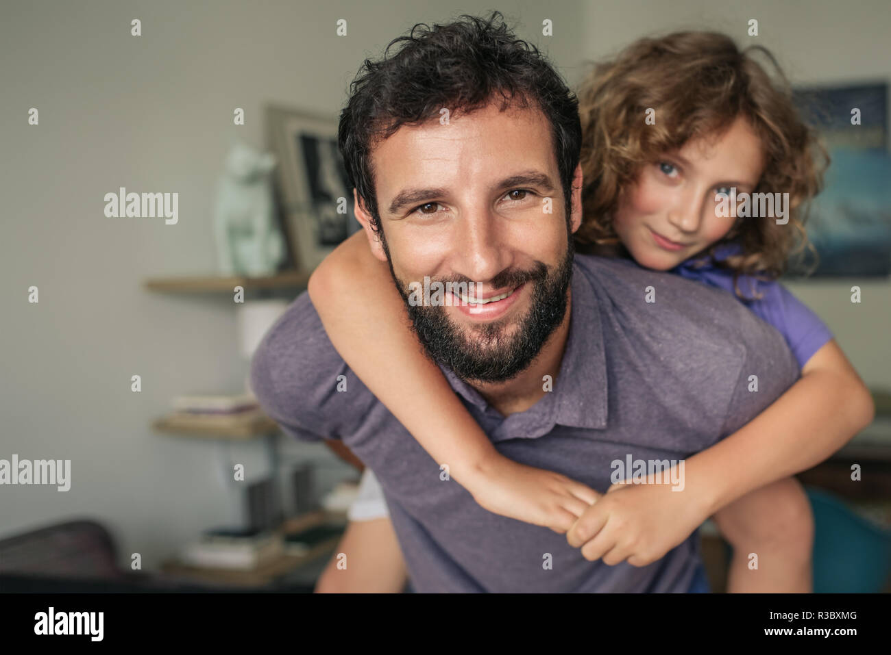 Happy father giving his son a piggyback at home Stock Photo