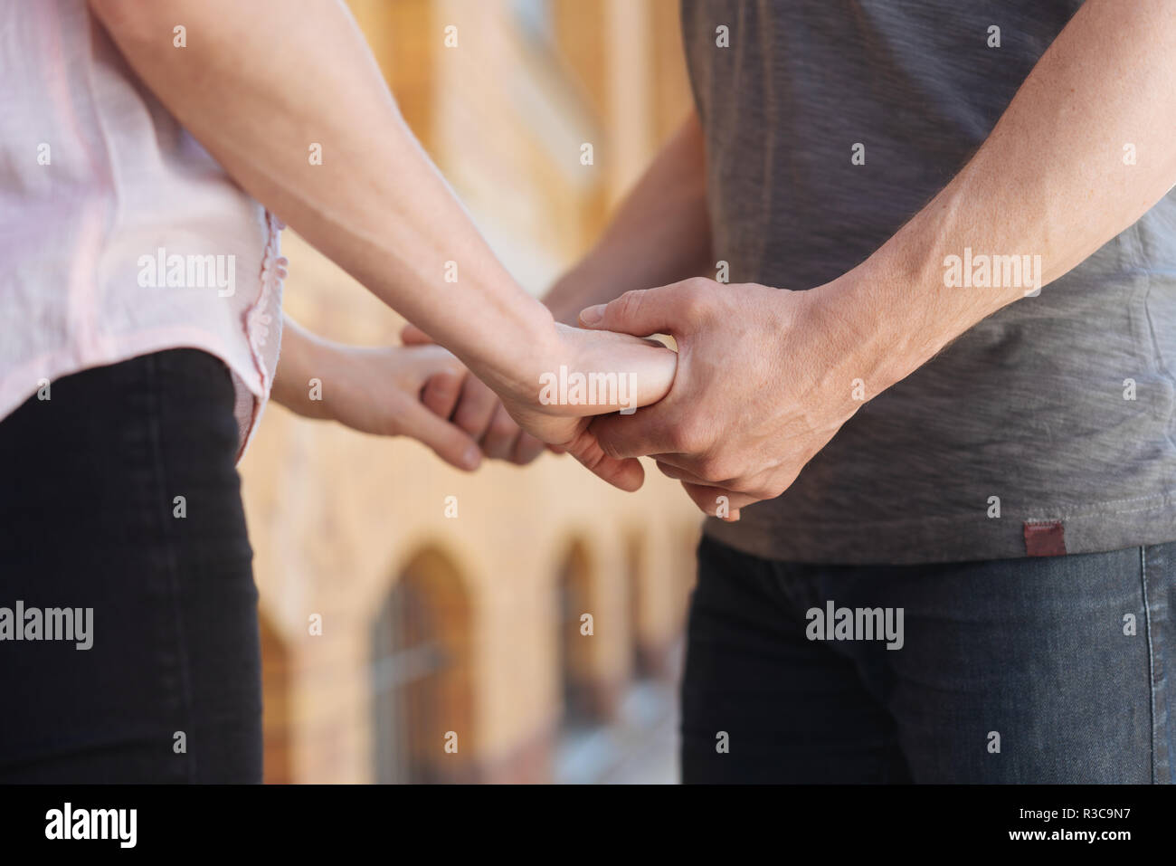 Loving young couple holding hands outdoors in an urban street clasping each other with both hands Stock Photo