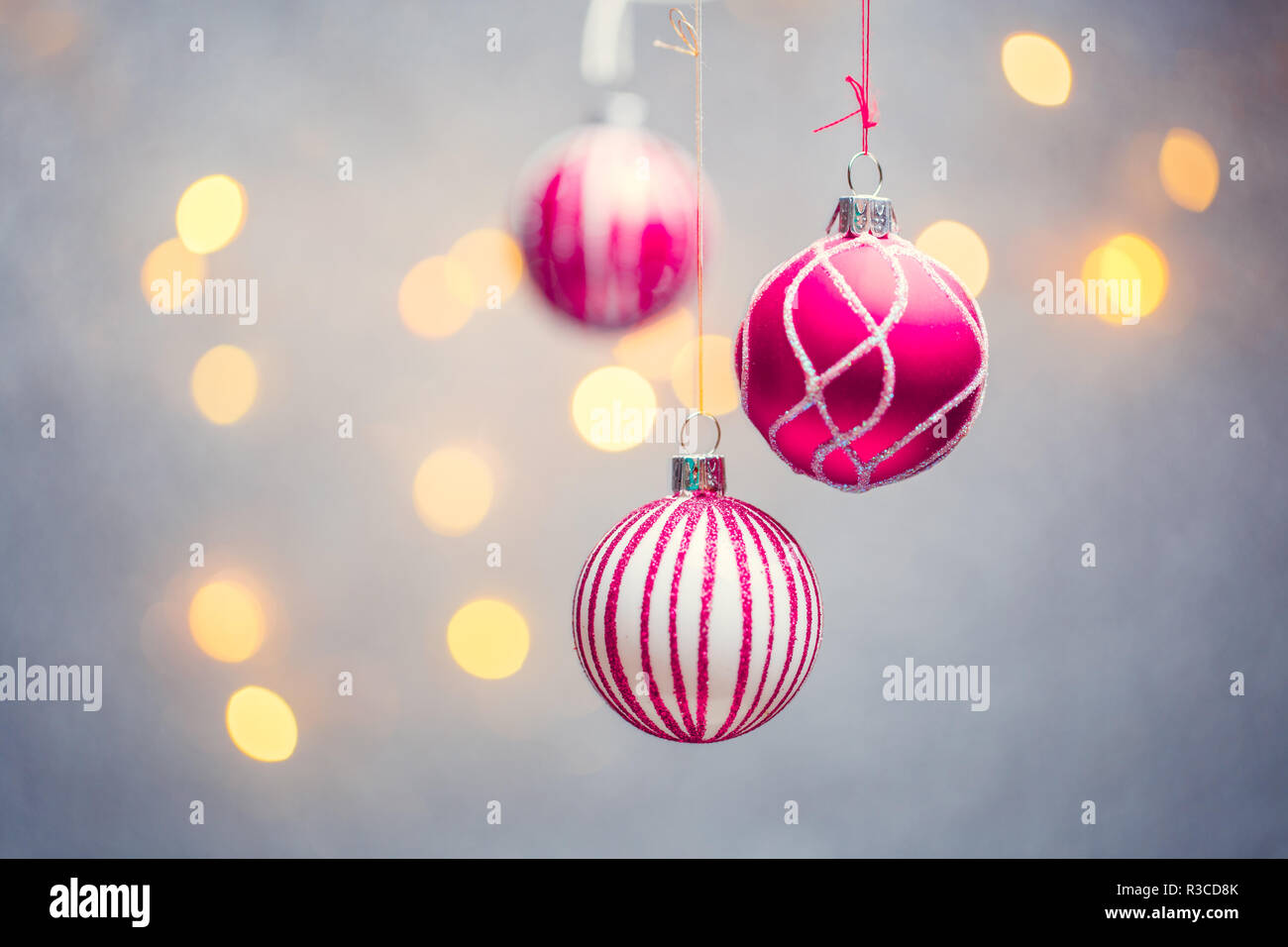 Picture of three Christmas pink balls with pattern on gray background with lights. Place for text Stock Photo