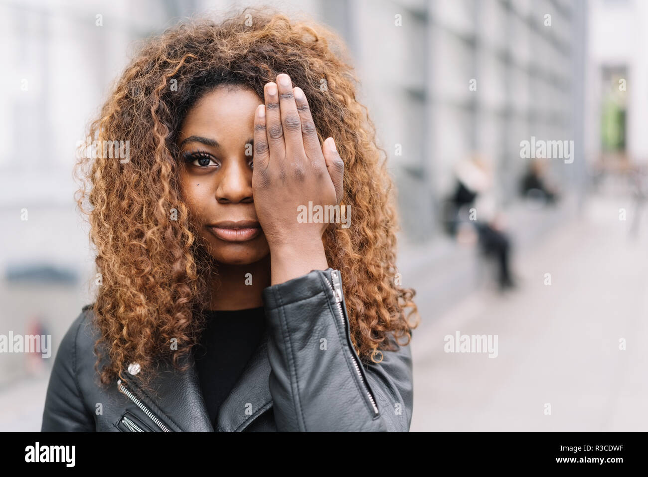 Young African woman covering on eye with a hand as she stands on an