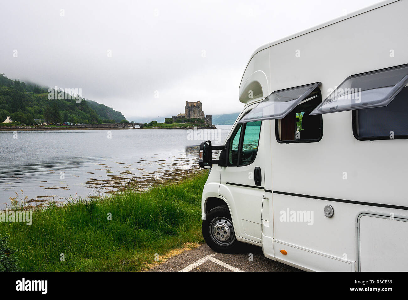 Camper car in front of Eilean Donan castle among scottish mist Stock Photo