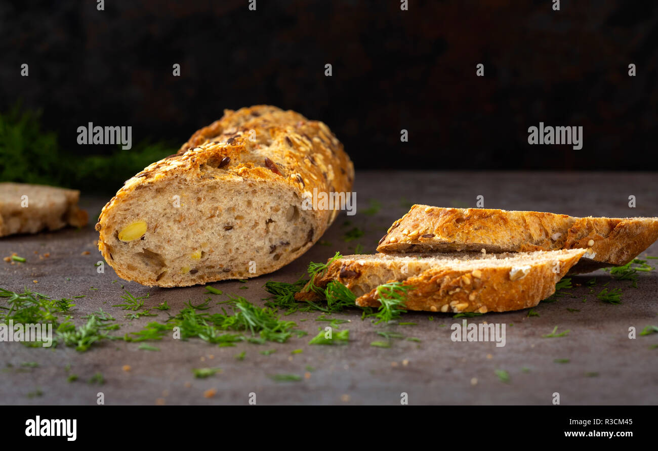 Bread with different seeds ( pumpkin, poppy, flax, sunflower, sesame, millet ) decorated with chopped green dill Stock Photo
