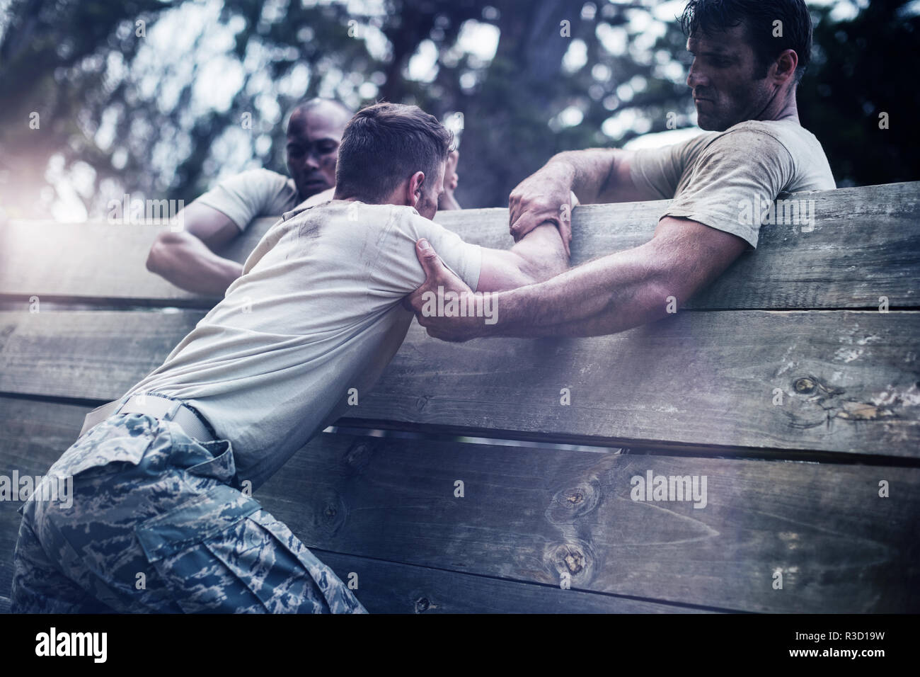 Soldiers helping man to climb wooden wall Stock Photo Alamy