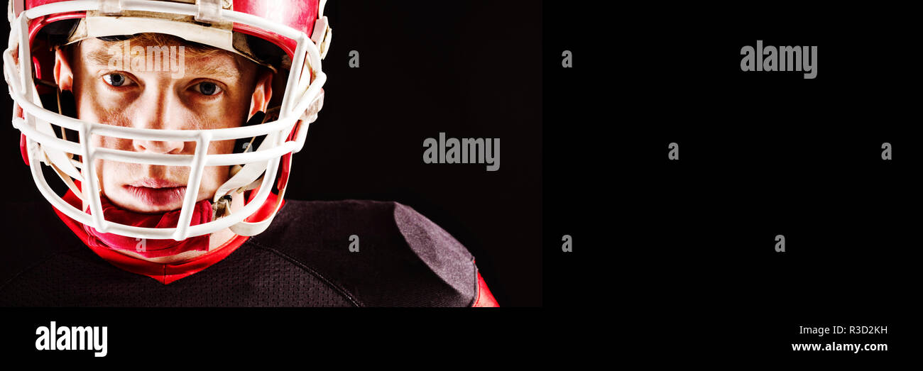 American football player in helmet standing against black background Stock Photo