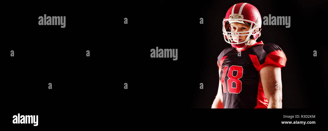 American football player in helmet standing against black background Stock Photo