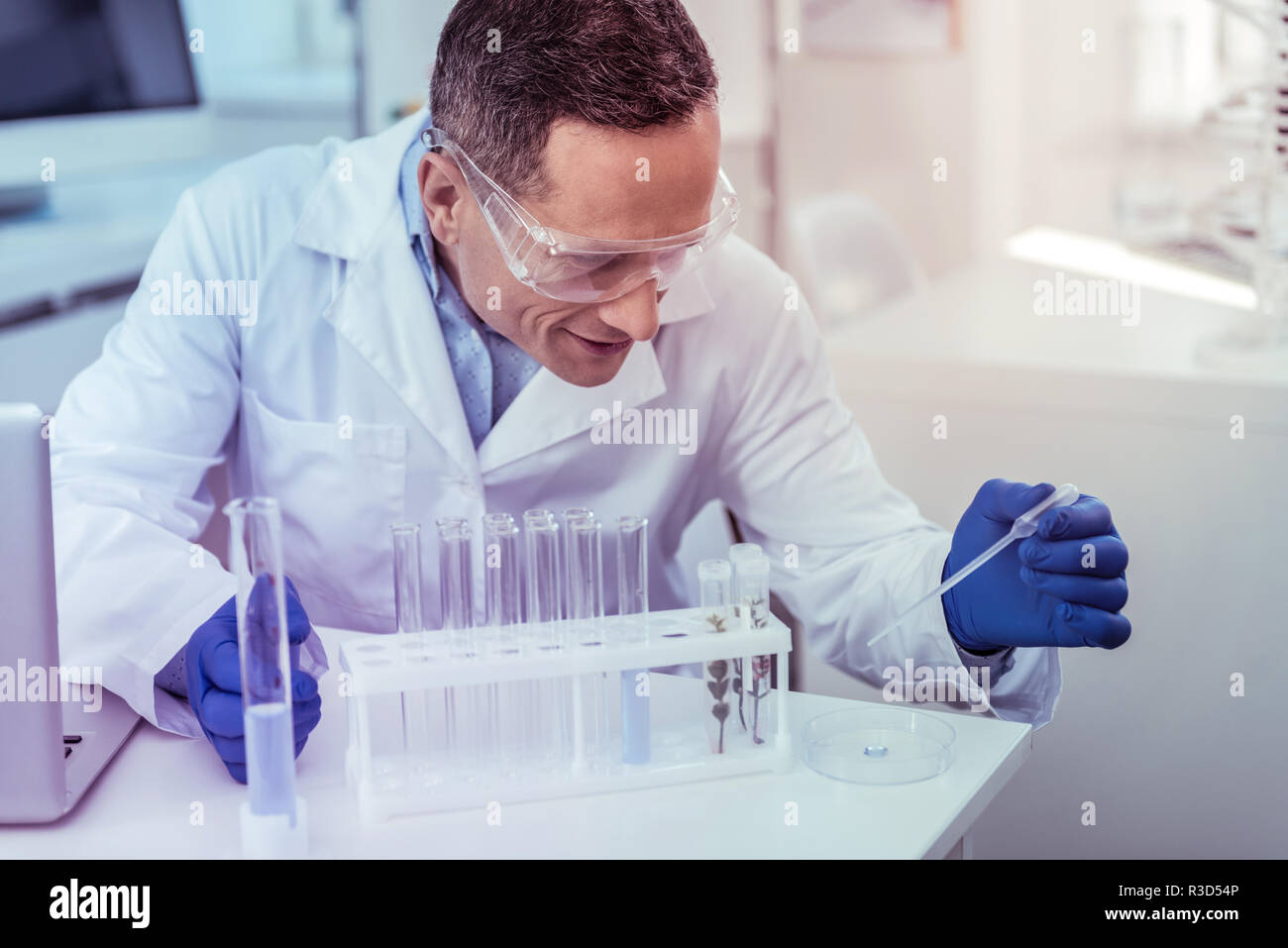 Scientific research. Cheerful medical worker keeping smile on his face while working in laboratory Stock Photo