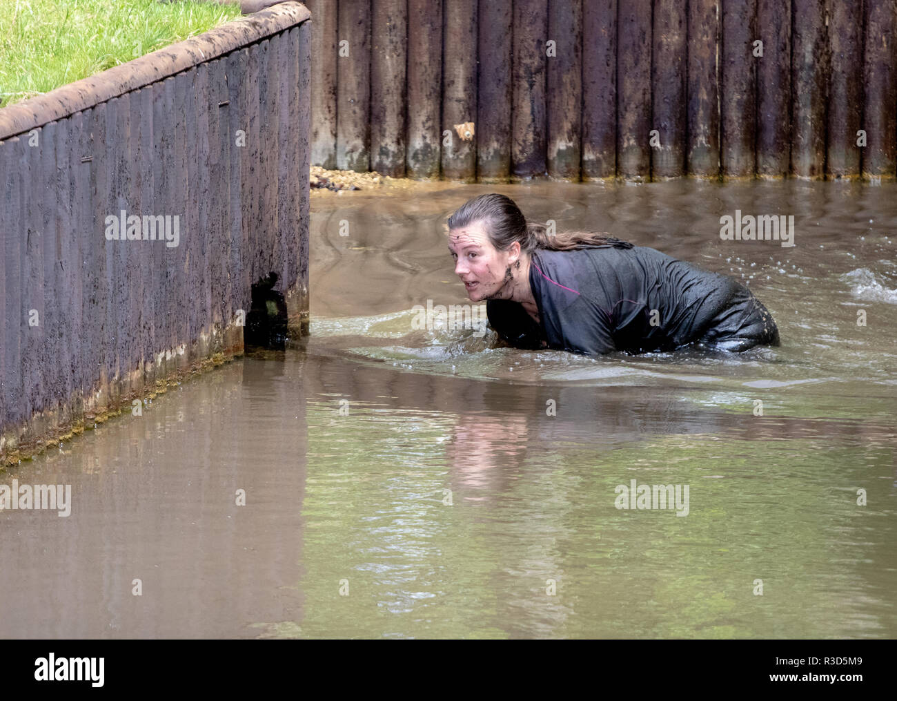 Rather soiled lady mud runner around a water crossing Stock Photo