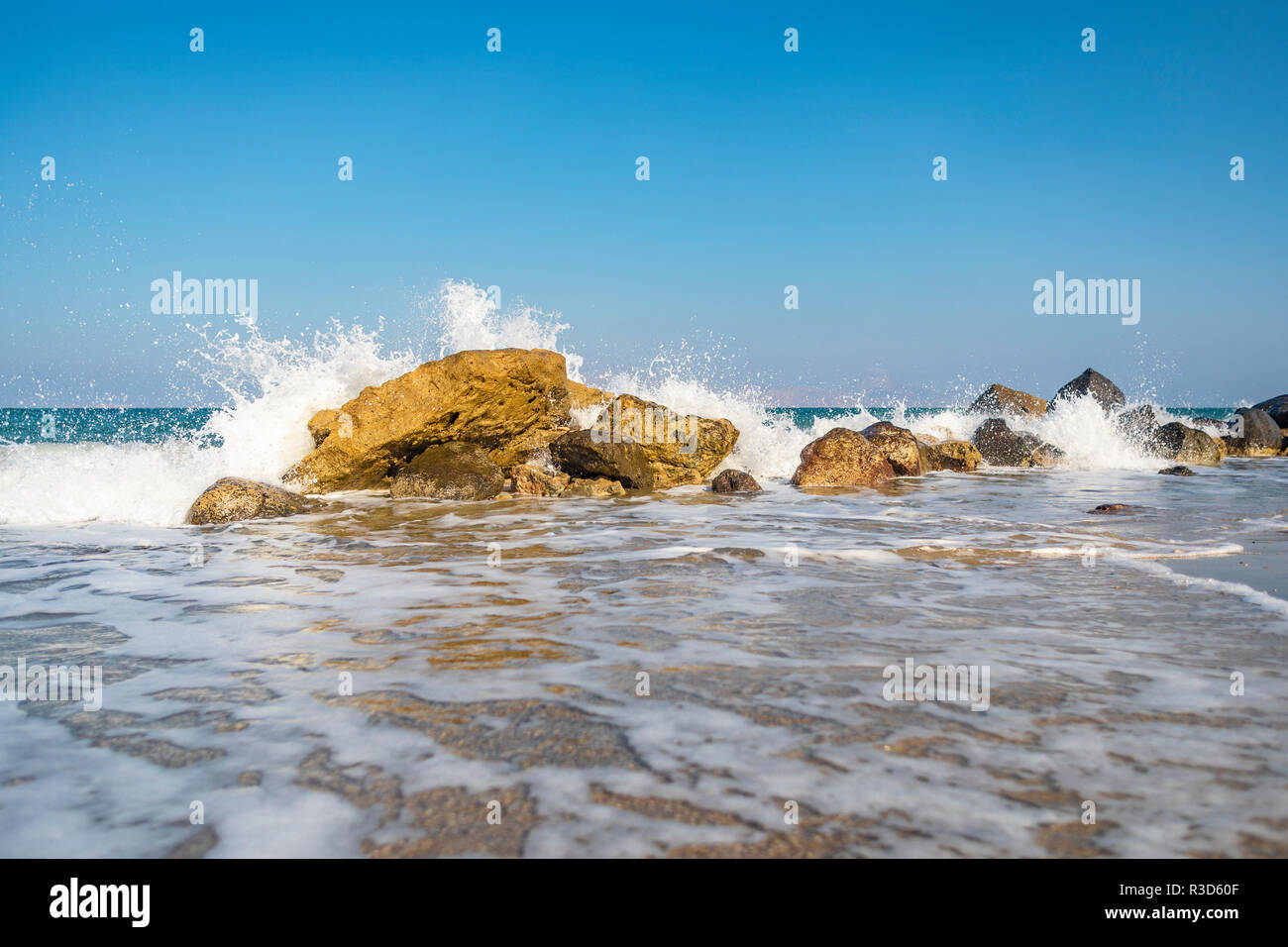 Greek island landscape depicting waves crashing down a formation of ...