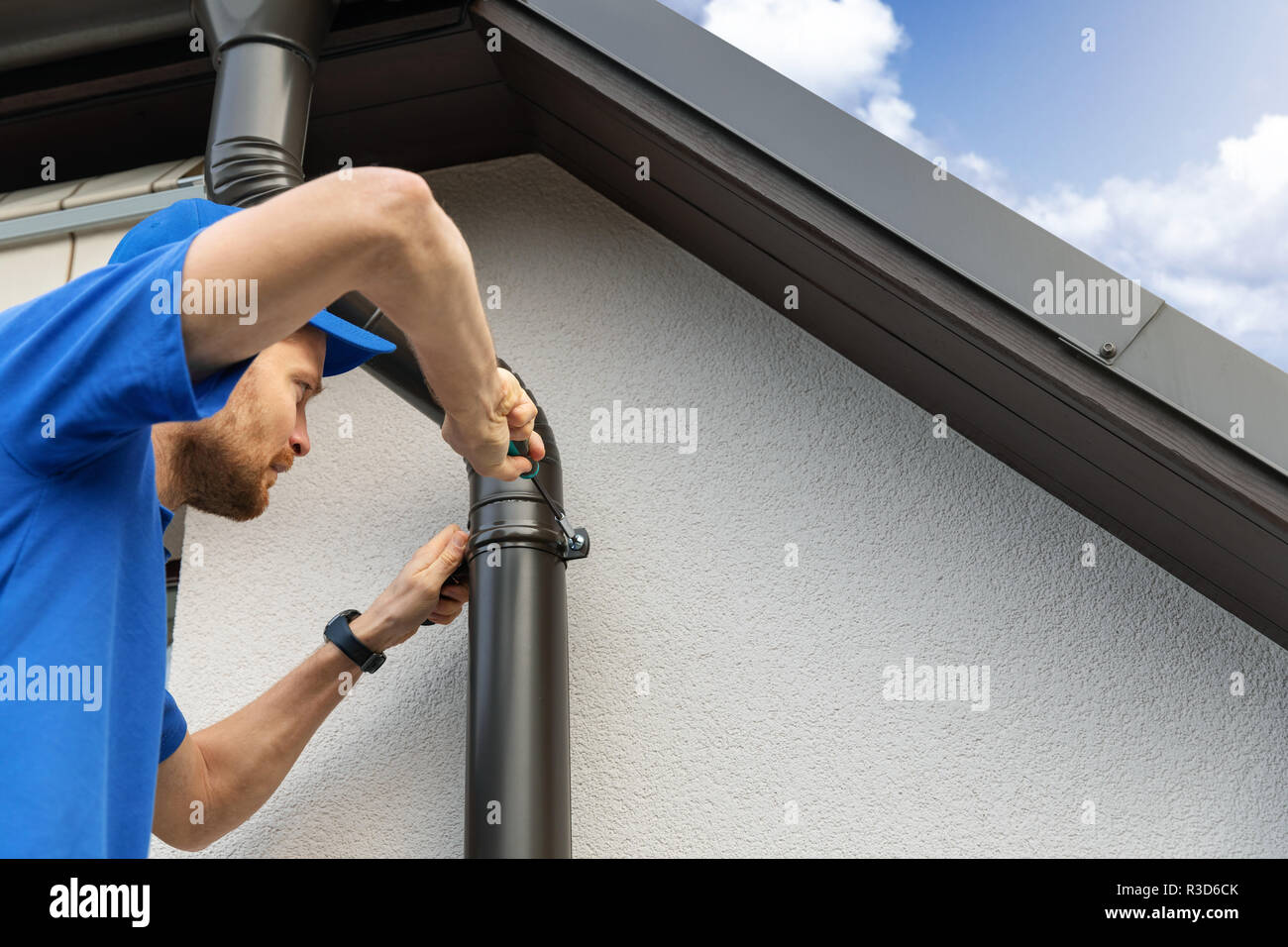 worker installing house roof gutter Stock Photo