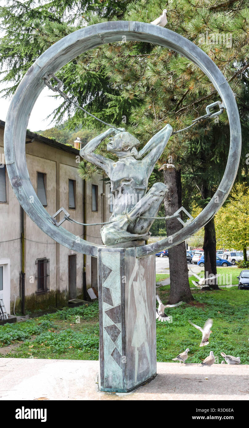 Contemporary war memorial statue containing a wire or rope-bound prisoner contained within a circle. A white dove perches atop the circle. Public art  Stock Photo