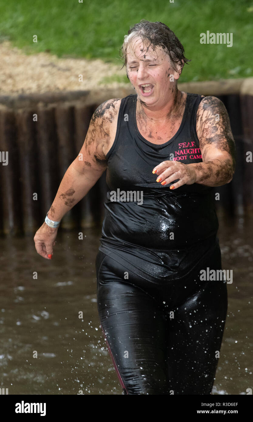Woman competing in an obstacle race runs through water Stock Photo