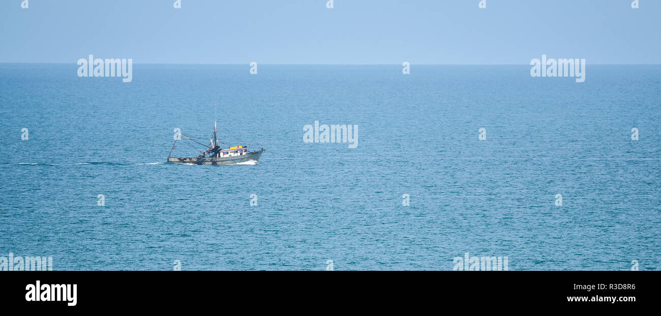 Fishing trawler boat on the Pacific Ocean heads out to sea on sunny summer day. Stock Photo