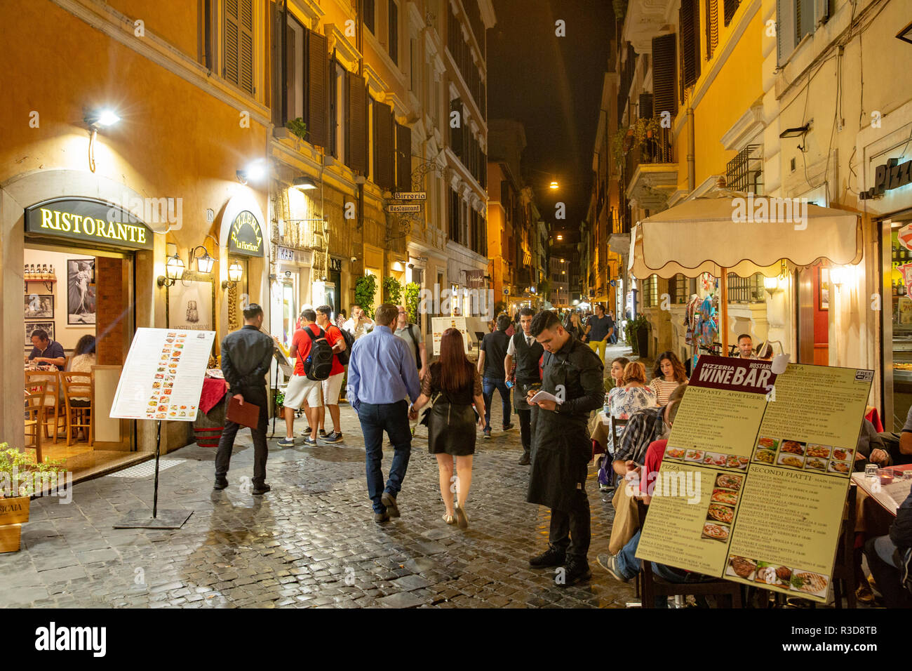 Night time scene in Rome as people walk along cobbled street looking for a restaurant or cafe for dinner, Rome,Italy,Europe Stock Photo