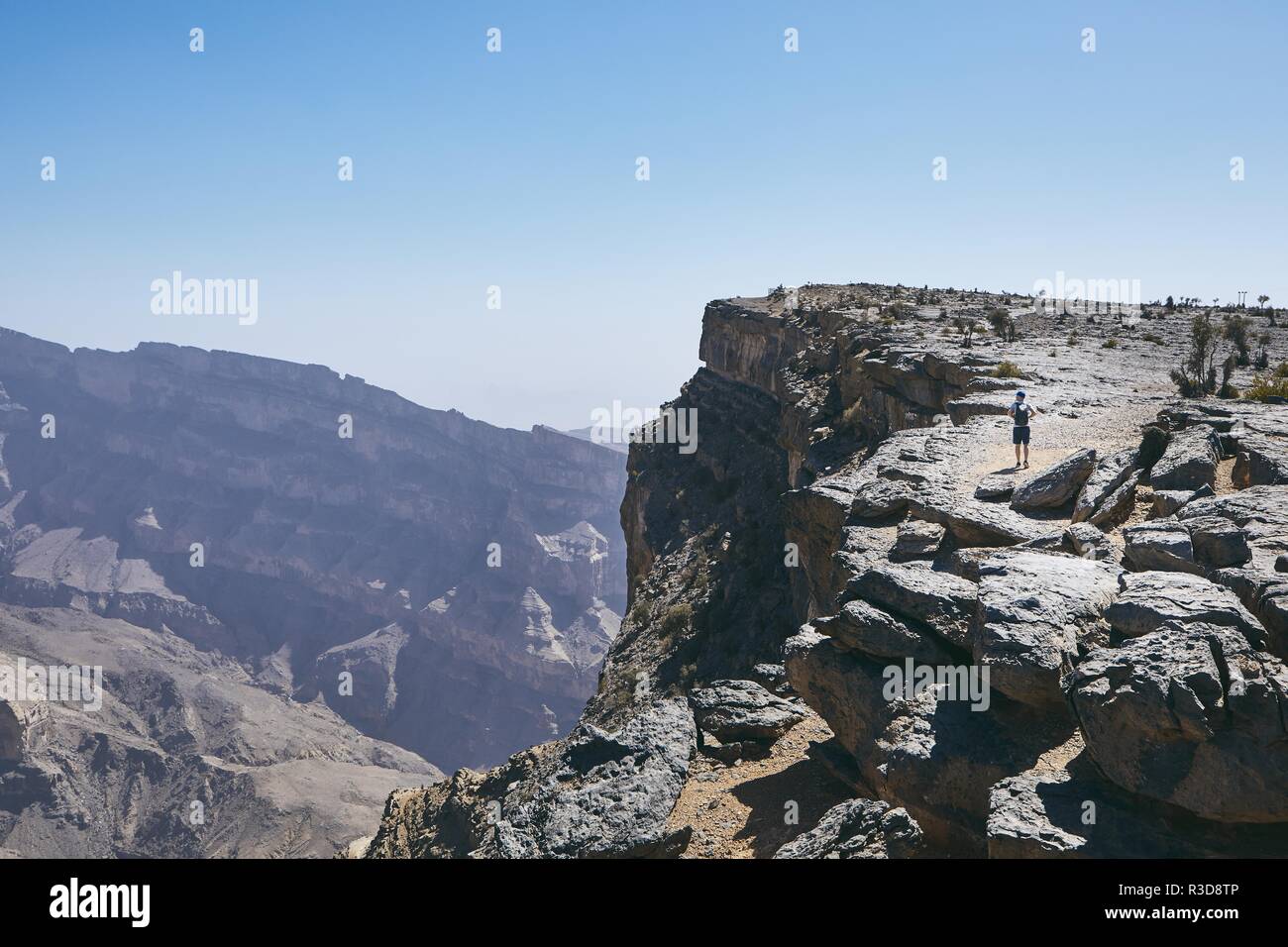 Grand Canyon of Oman. Tourist walking on the edge of cliff. Mountain range Jebel Akhdar. Stock Photo