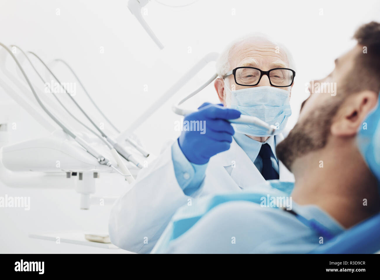 Oral hygiene. Low angle of ambitious male dentist using tool while