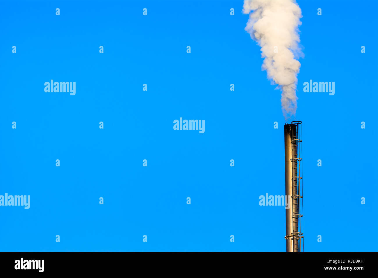 Power plant smokestack with carbon emission - co2, dioxide or fossil fuel. Air pollution by industry. Chimney and smoke cloud on blue sky background. Stock Photo