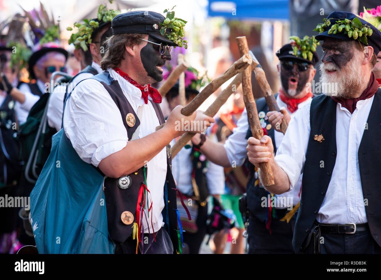 Faversham hop festival. Dead Horse and the broomdashers Morris side, with blacked faces, folk dancing and bashing wooden poles together. Close up. Stock Photo