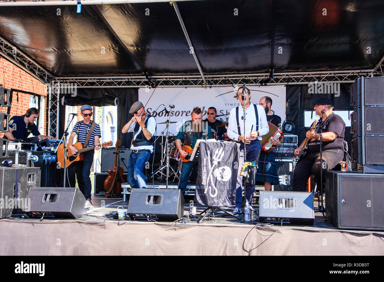 Faversham Hop Festival 2018. French rock folk band, Sur Les Docks performing on covered stage with Pierrot singing. Daytime. Stock Photo
