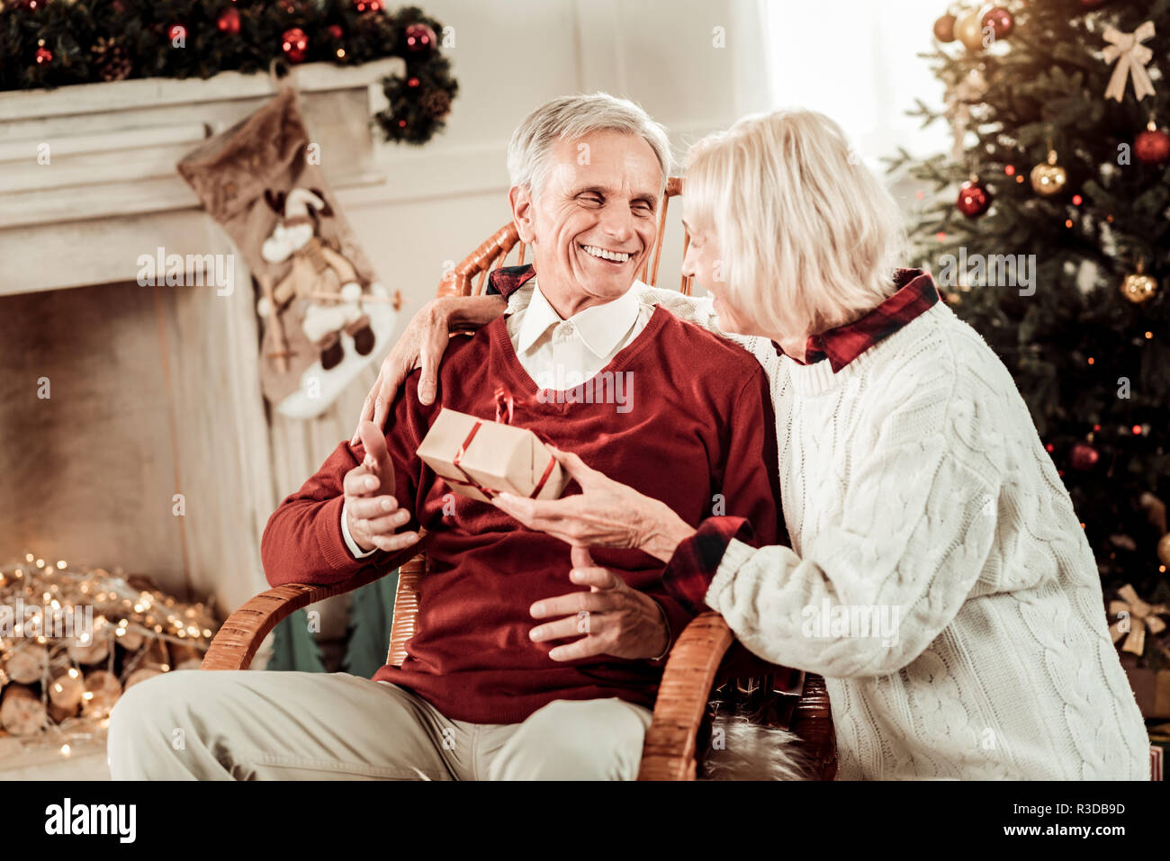 Unexpected gift. Surprised happy aged man sitting on the chair