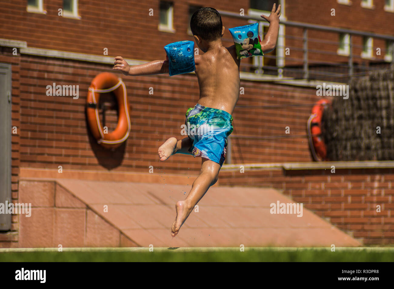Niño saltando a la piscina en vacaciones. Stock Photo