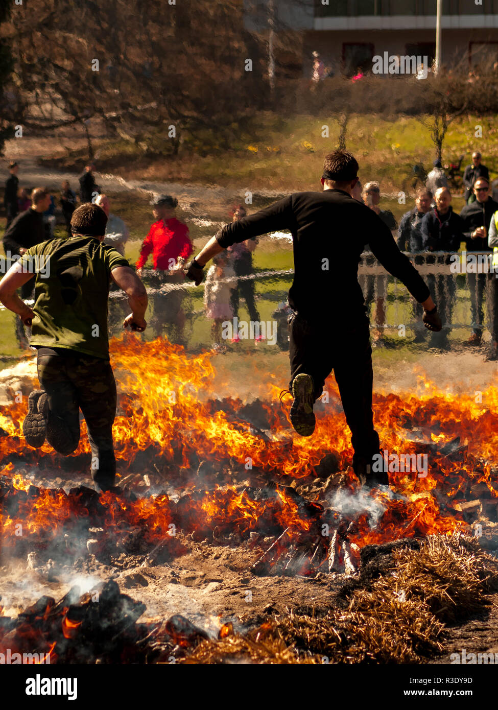 Brave people jumping over fire during the obstacle course race Tough Viking in Slottsskogen, Gothenburg, Sweden Stock Photo