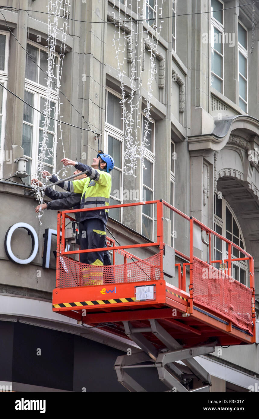 Workers on an orange scissorlift scaffold installing Christmas lights on the front of a retail building in the Old Town section of Lucerne, Switzerlan Stock Photo