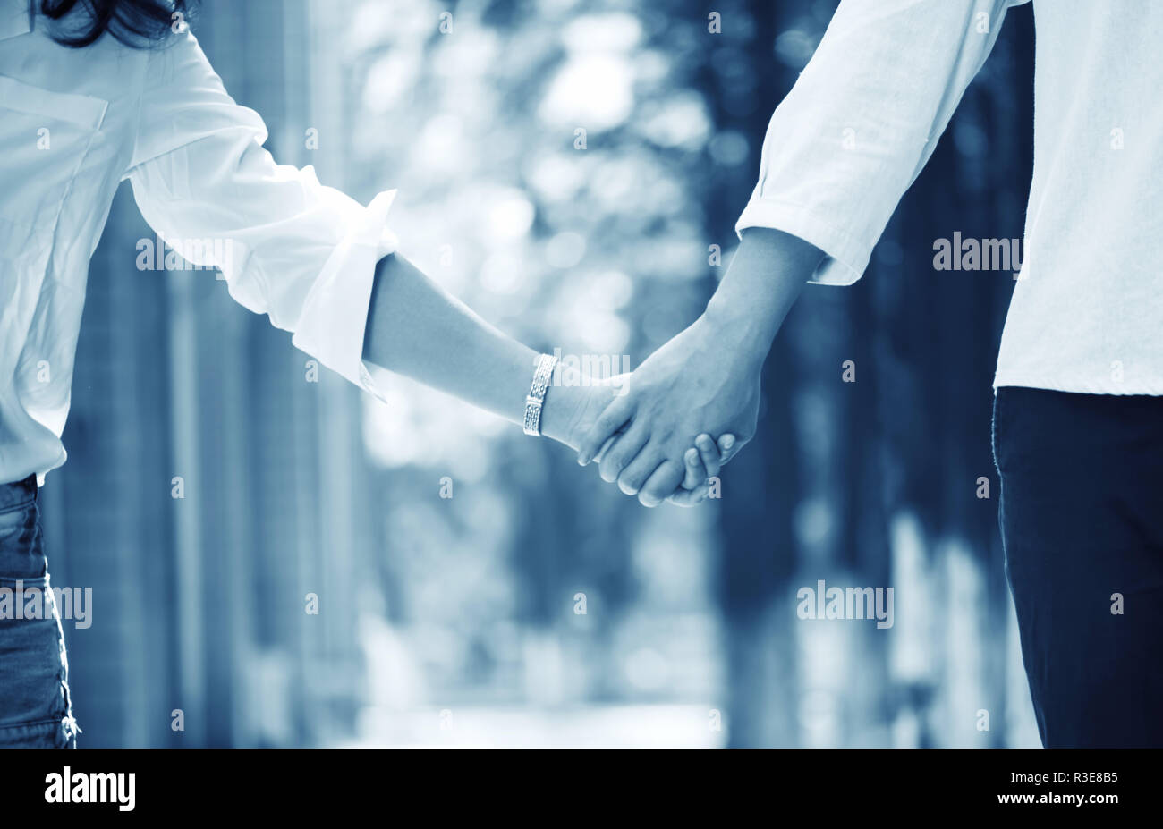 Happy couple holding hands looking Stock Photo - Alamy