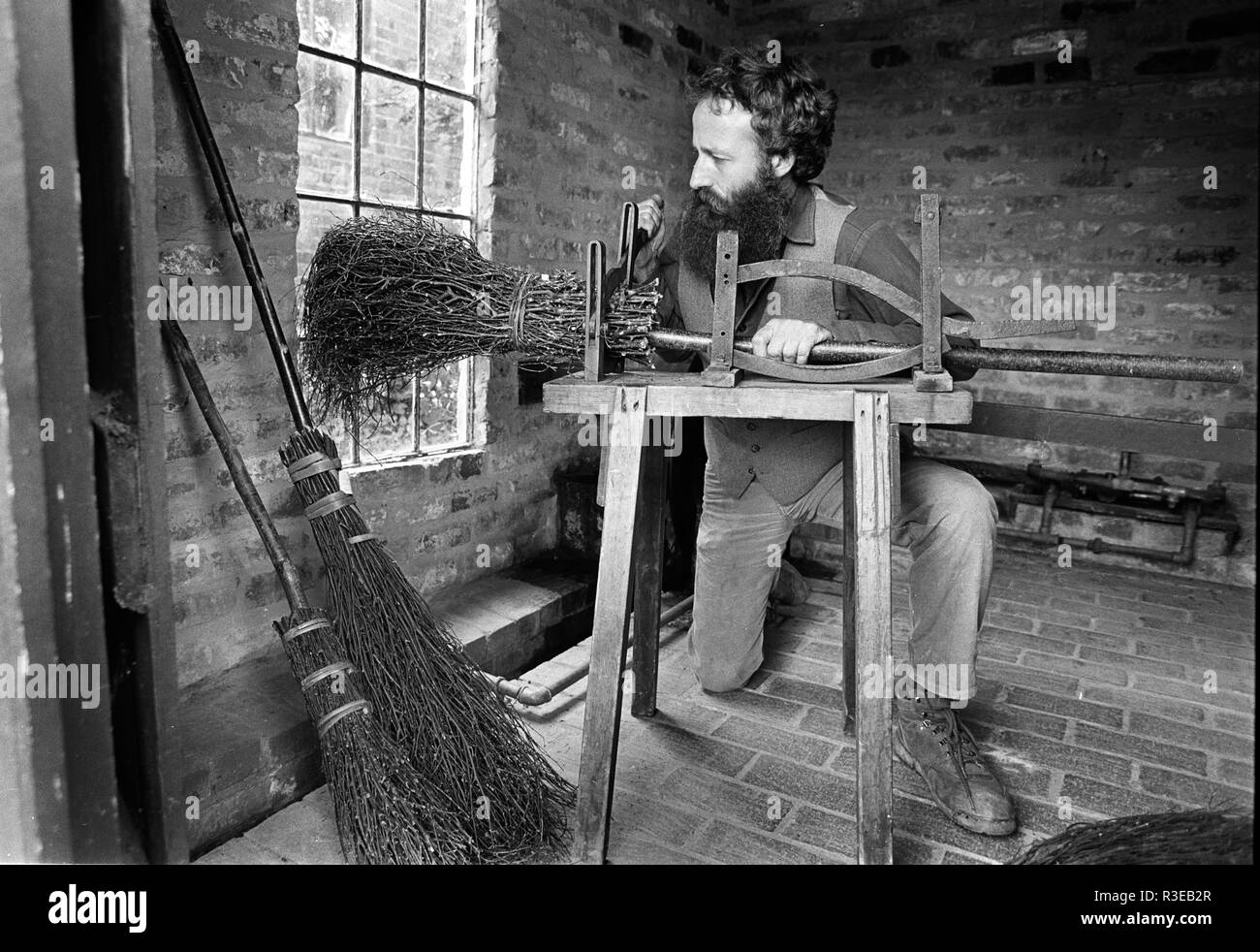 A Shropshire besom maker uses a traditional Victorian machine to bind the switches that make the brush Stock Photo