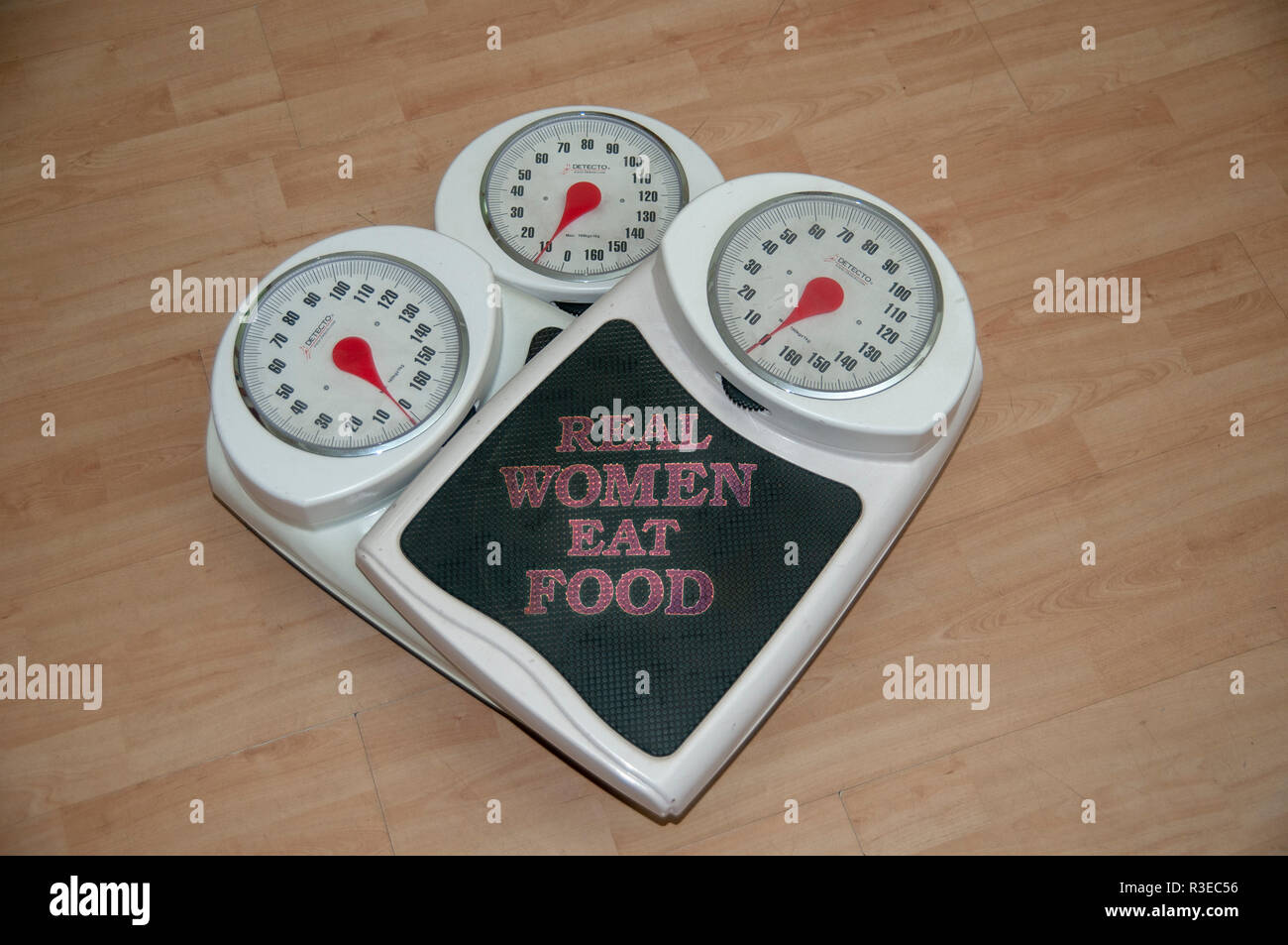Dieting, weight loss and body image conceptual image of three analogue scales stacked one on top of the other with the text of 'Real Women eat food' Stock Photo