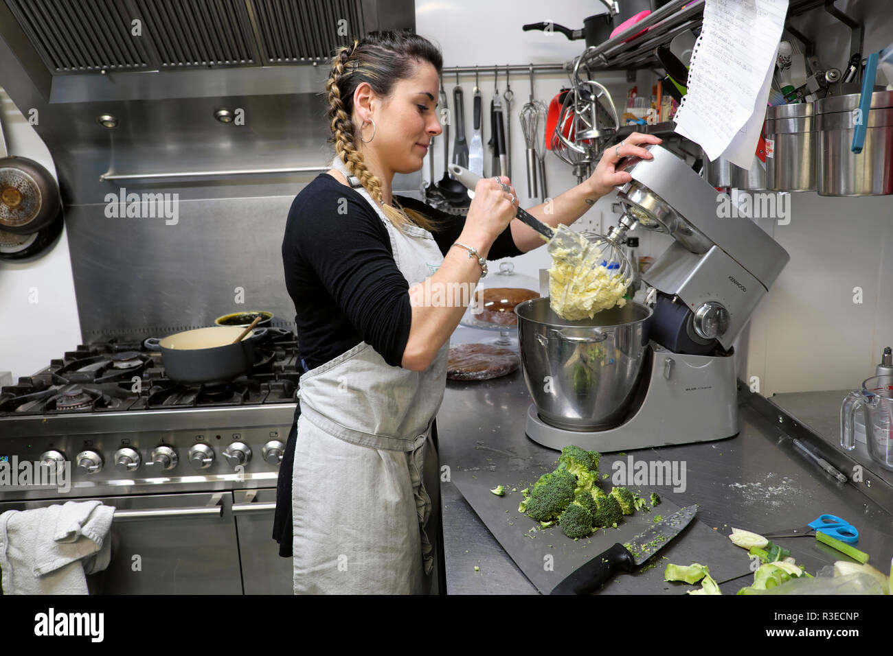 A smiling young female chef preparing food in the kitchen of the contemporary Old Printing Office cafe restaurant in Llandovery Wales UK  KATHY DEWITT Stock Photo