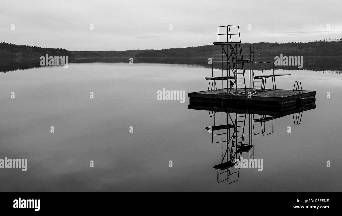 A jetty in tranquil water black and white in Teåkersjön, Dalsland Sweden Stock Photo