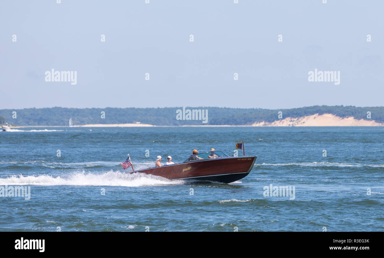 four people on a old wooden power boat enjoying the water Stock Photo