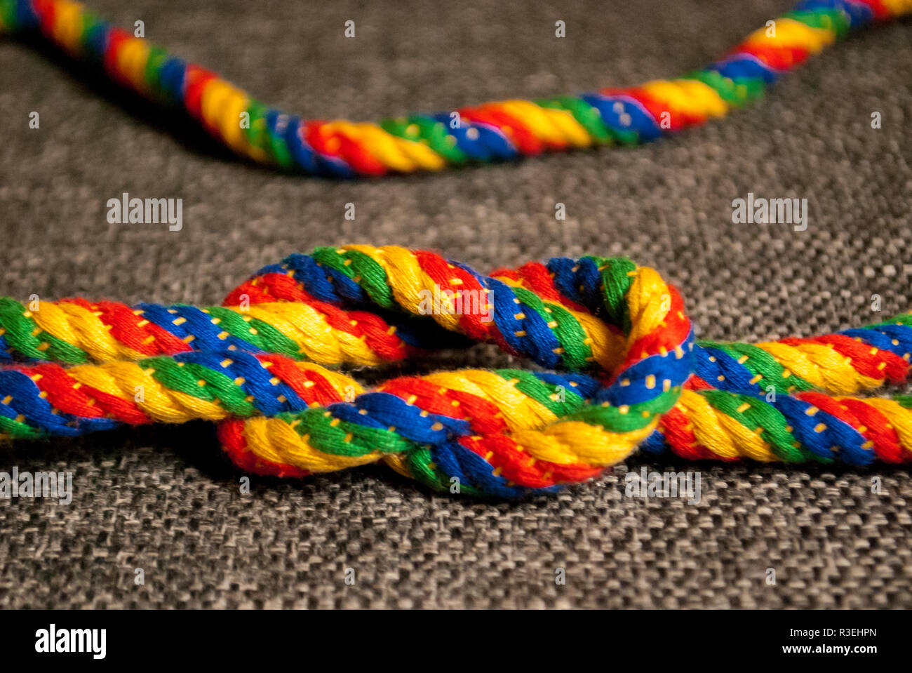 A rainbow colored rope tied into a reef knot Stock Photo - Alamy