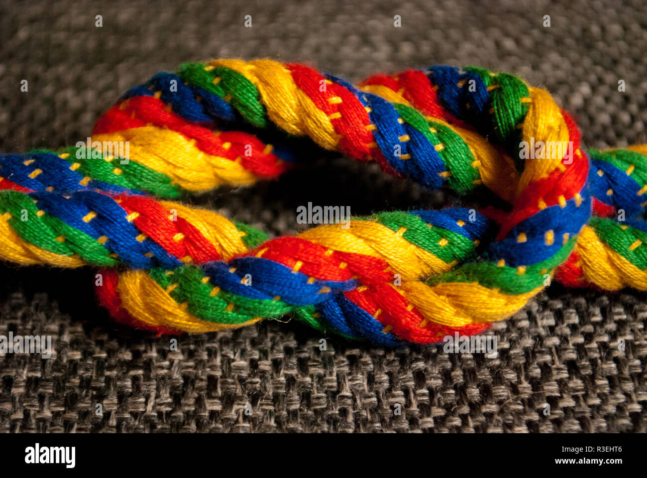 A rainbow colored rope tied into a reef knot Stock Photo