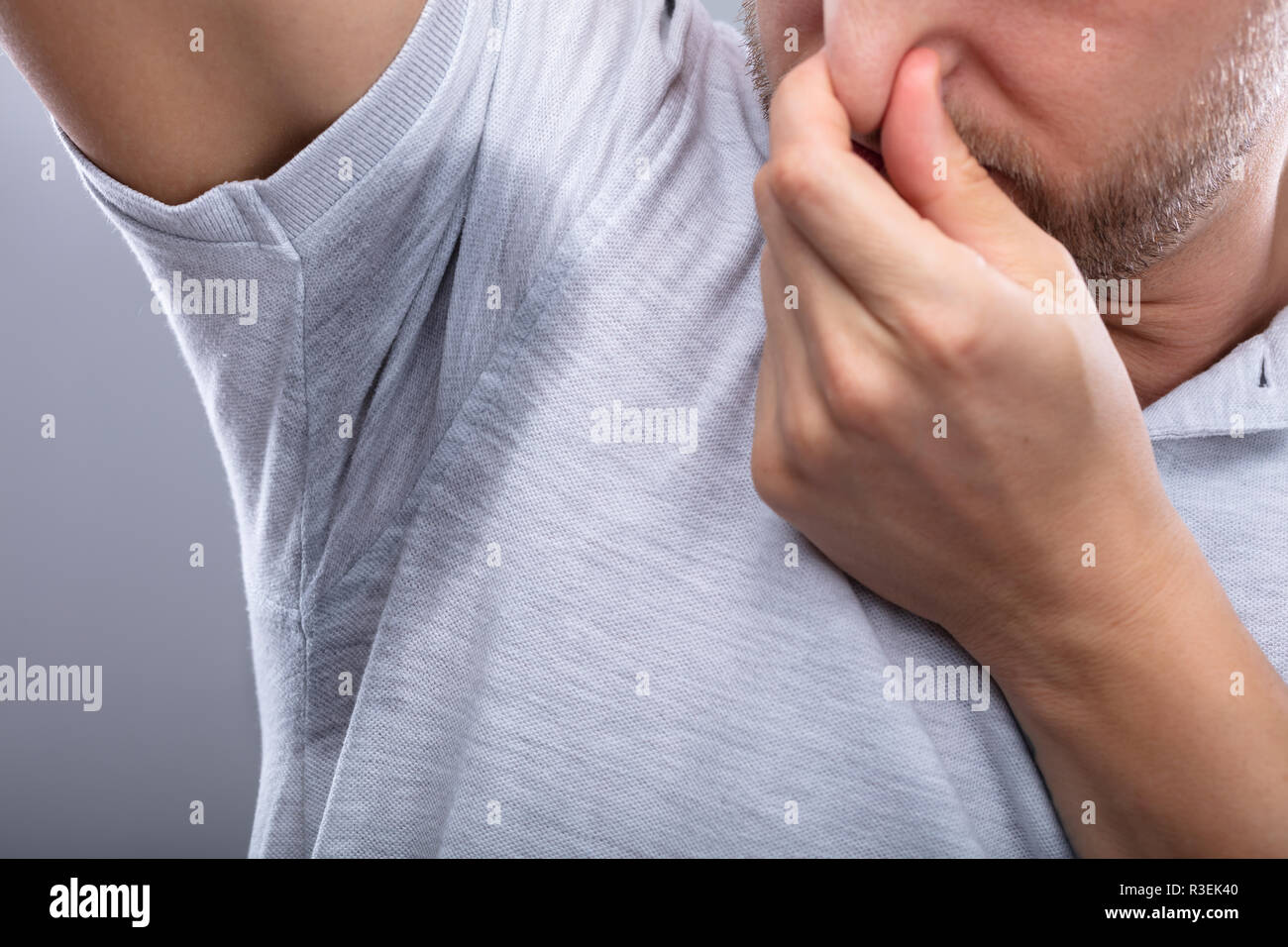 Close-up Of A Man With Sweaty Armpit Covering His Nose With Hand Stock Photo
