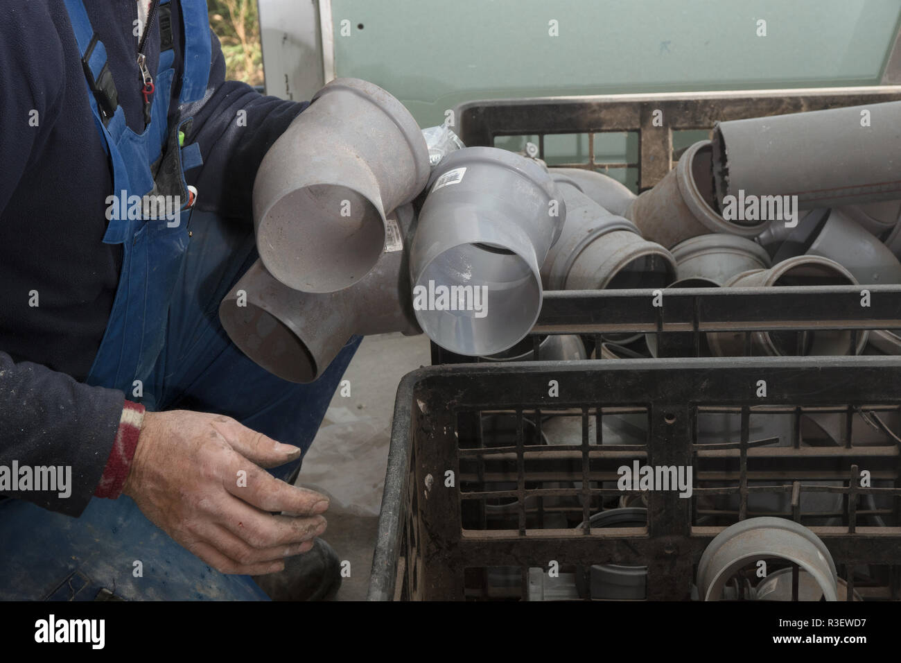 sanitary installer searches in a big box  for a suitable connection bend for the waste water pipe, selected focus Stock Photo
