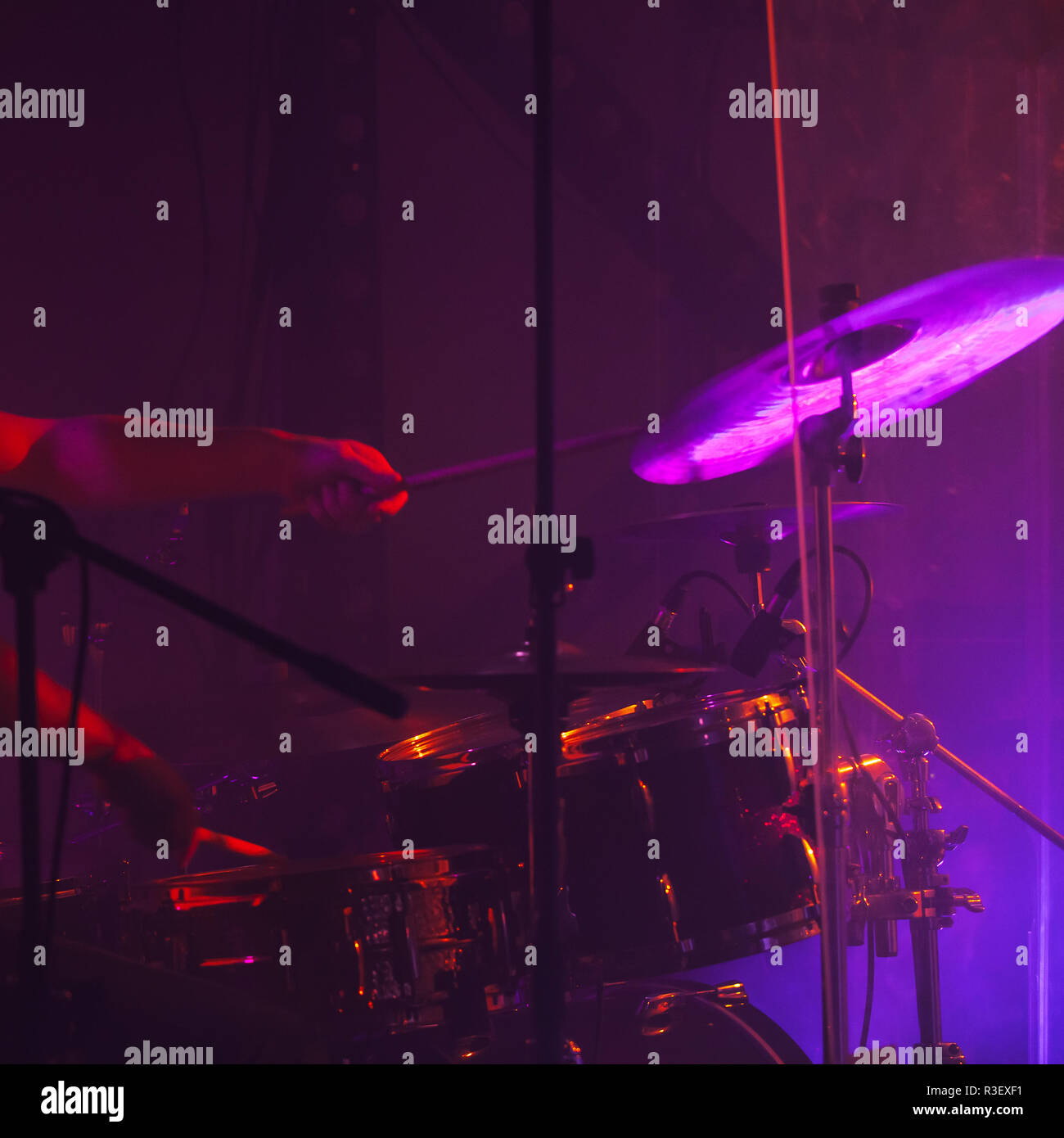 Live rock music photo background, drummer plays on rock drum set  with cymbals in purple stage lights. Close-up photo, soft selective focu Stock Photo