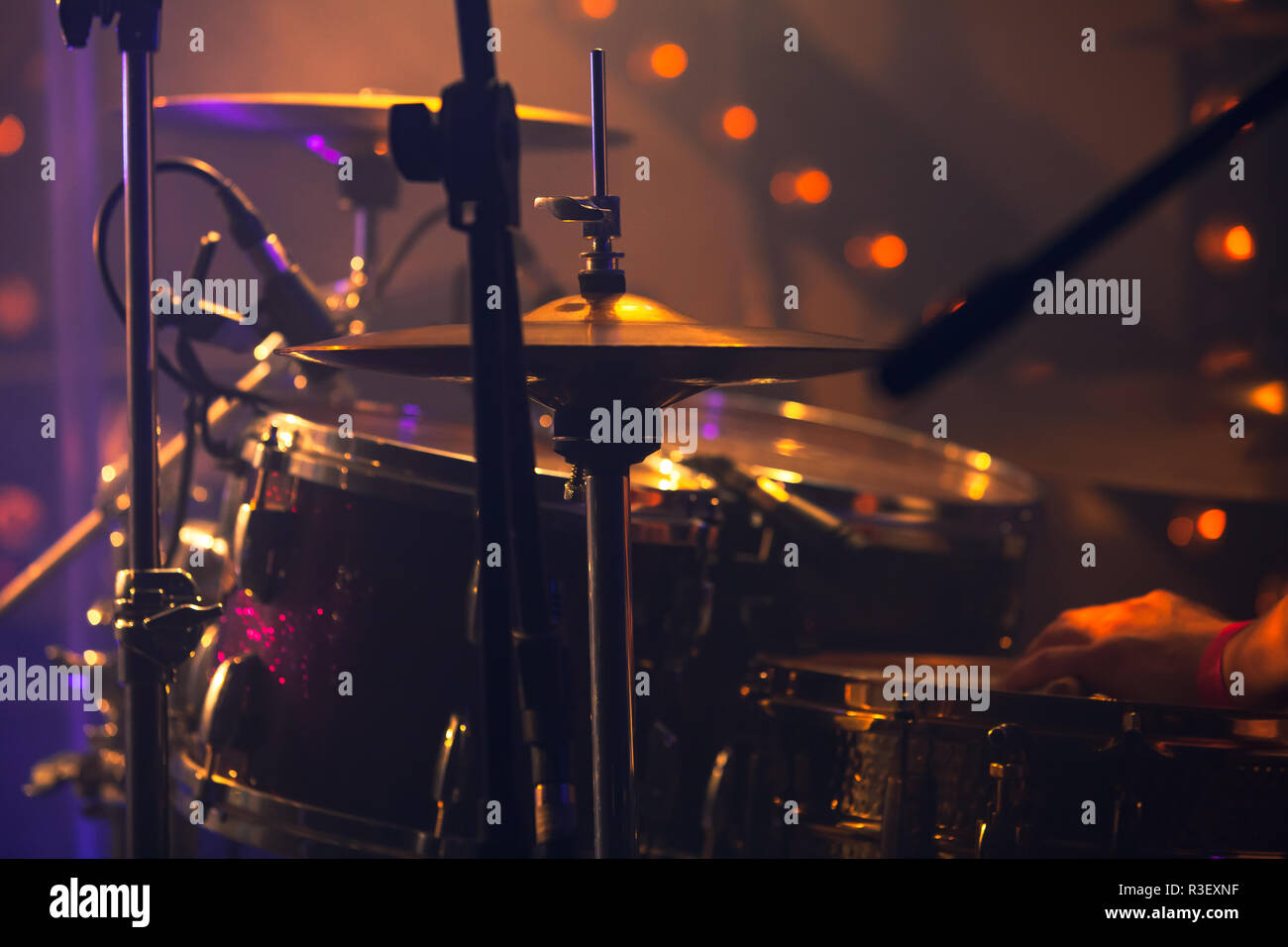 Rock music background, drummer plays with drumsticks on rock drum set. Warm toned close-up photo, soft selective focus Stock Photo