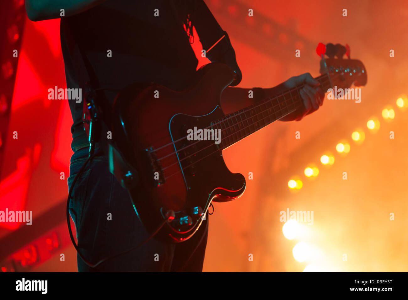 Electric bass guitar player in bright stage lights, close-up silhouette photo with soft selective focus Stock Photo
