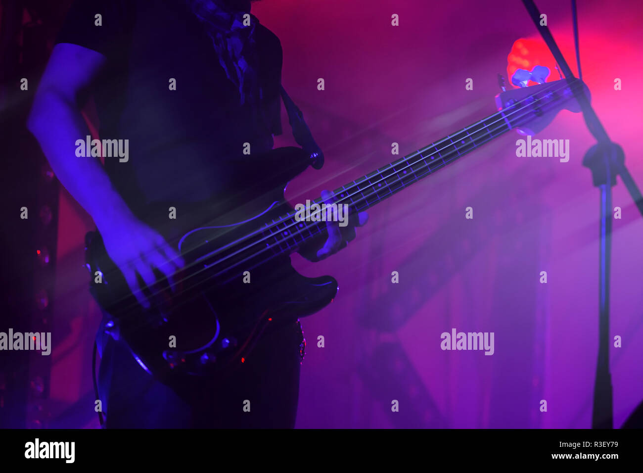 Electric bass guitar player on a stage in purple illumination, photo background with motion blur effect Stock Photo