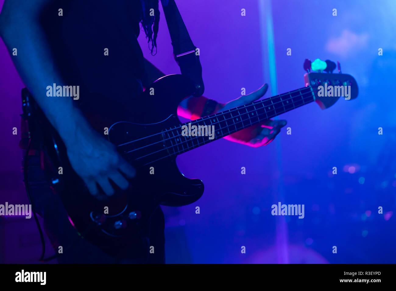 Live rock music background, bass guitar player on a stage, close-up photo with soft selective focus Stock Photo