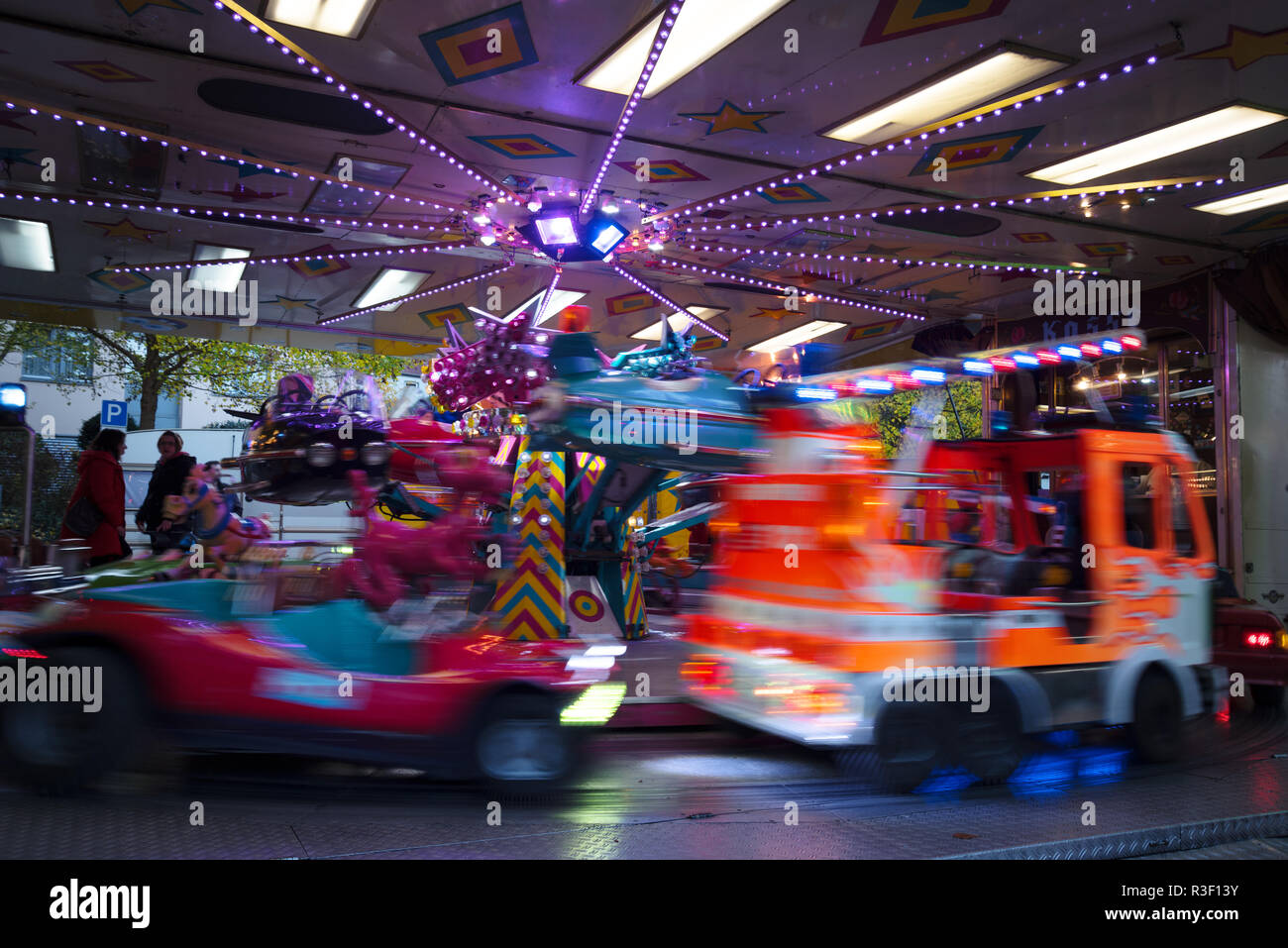 children's carousel with fire truck and cars at the christmas funfair market, long time exposure with blurred motion, abstract background, copy space Stock Photo