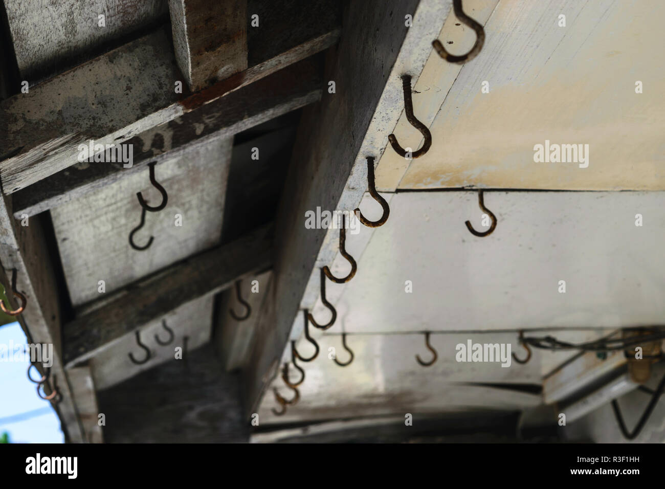 Background surface of old and rusty hooks hanging on the roof Stock Photo